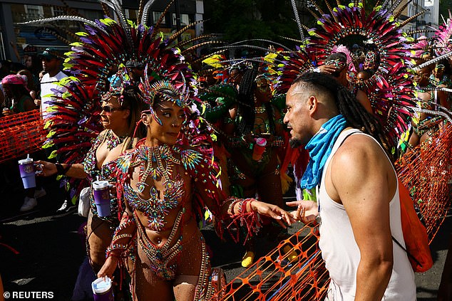 A man speaks to a woman dressed in a flamboyant, detailed and bright Carnival outfit