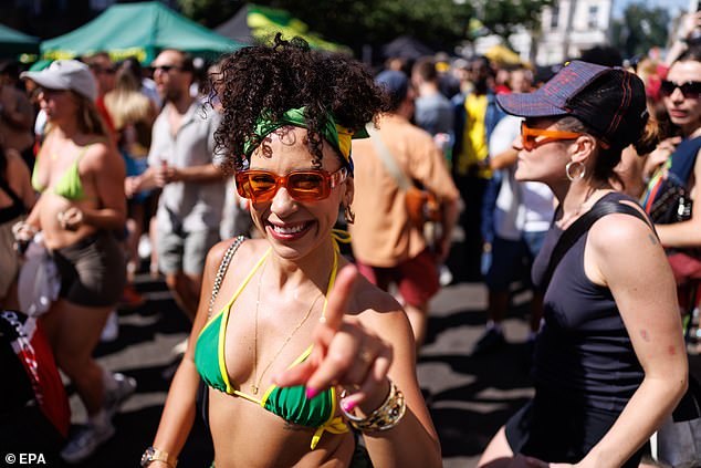 One carnival attendee wearing a green and yellow bikini and matching headband smiles as she enjoys the music