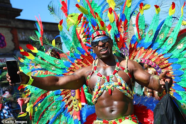 A reveller in elaborate and colourful costume takes part in the Notting Hill Carnival
