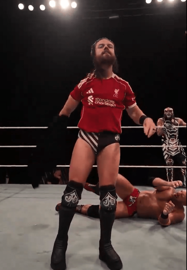 Wrestler standing over a fallen opponent in a wrestling ring.