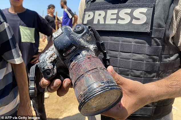 A journalist holds a blood-covered camera belonging to Palestinian photojournalist Hussam al-Masri, a Reuters contractor who was killed in an Israeli strike on Nasser hospital in Khan Yunis in the southern Gaza Strip, during his funeral on August 25, 2025