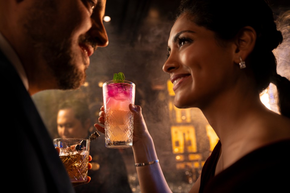 Couple toasting with cocktails at a bar.