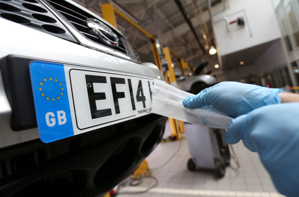 Mechanic attaching license plate to car.