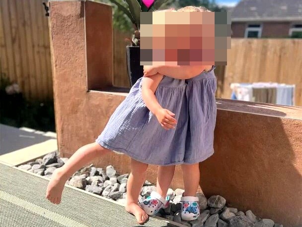 Two toddlers hugging outdoors.