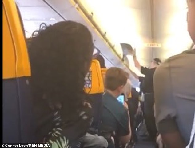 Police were seen opening one of the overhead compartments on the plane as they removed the passenger