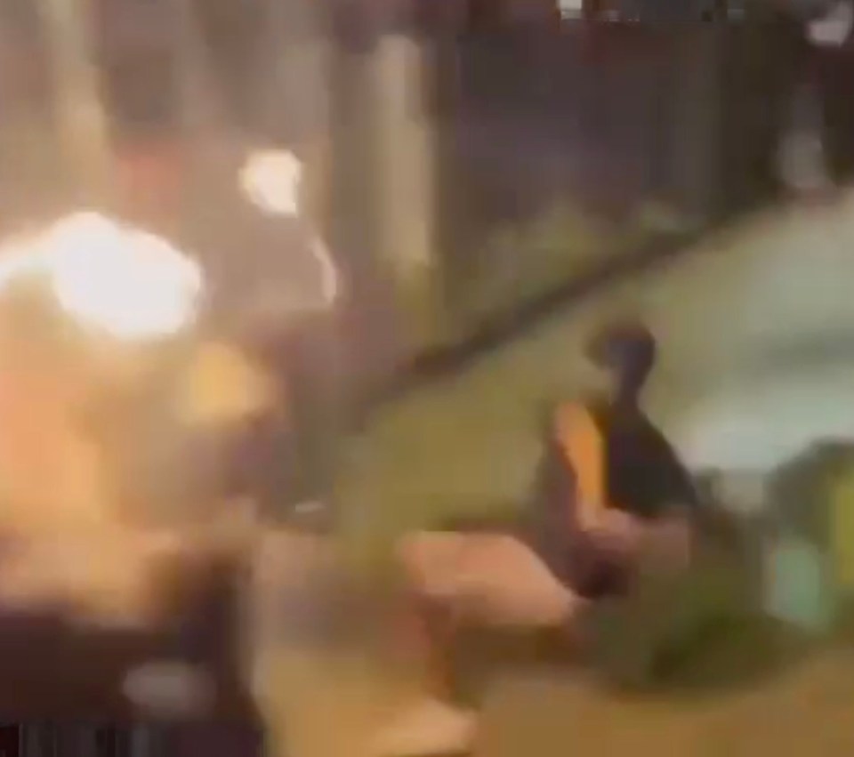 Blurry video of a bull with flaming torches on its horns charging a person.
