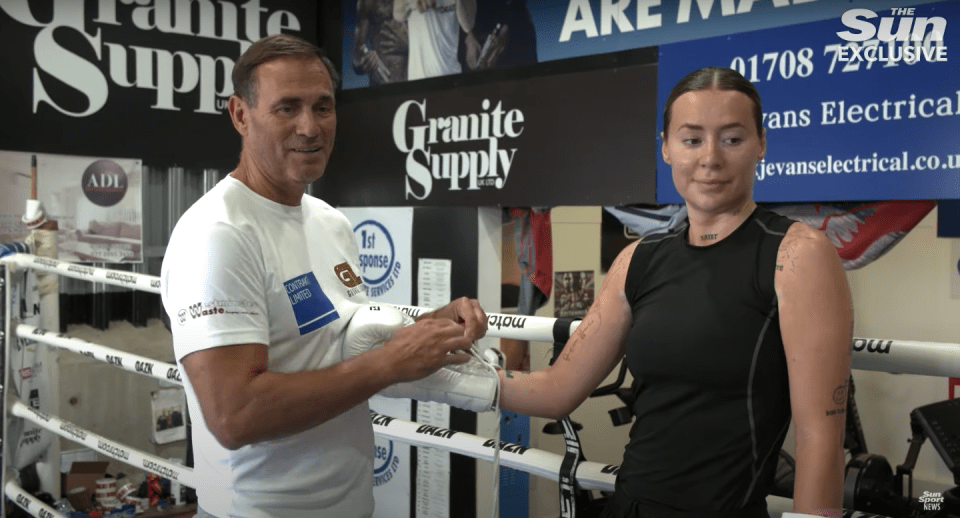 A man helps a woman put on boxing gloves.