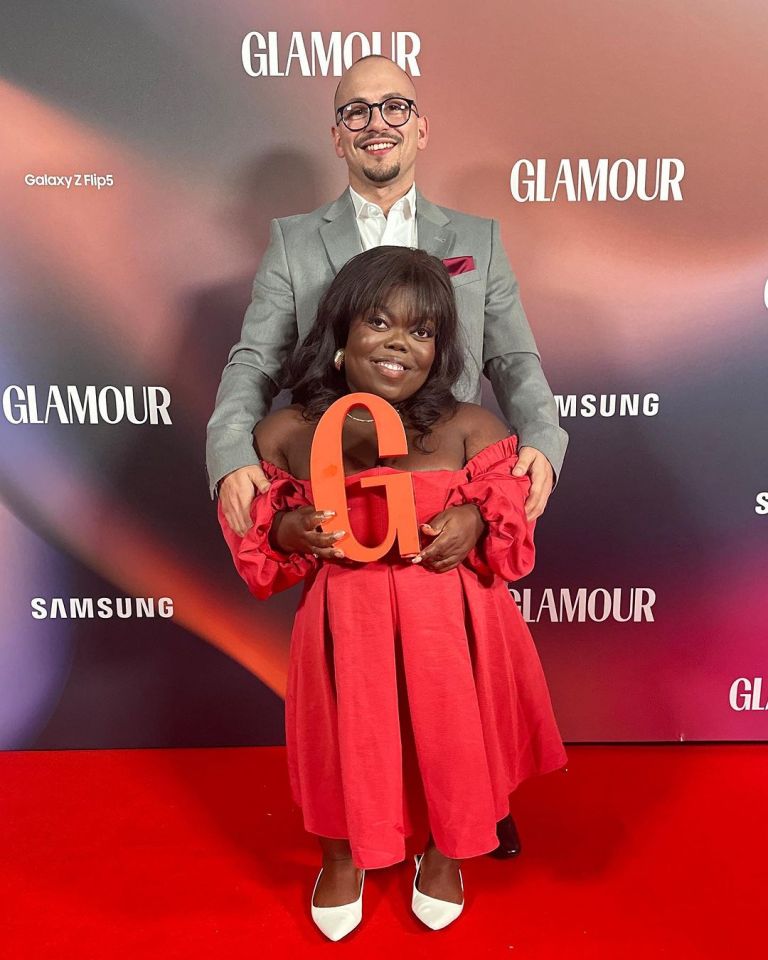 a man and a woman are posing for a picture in front of a wall that says glamour
