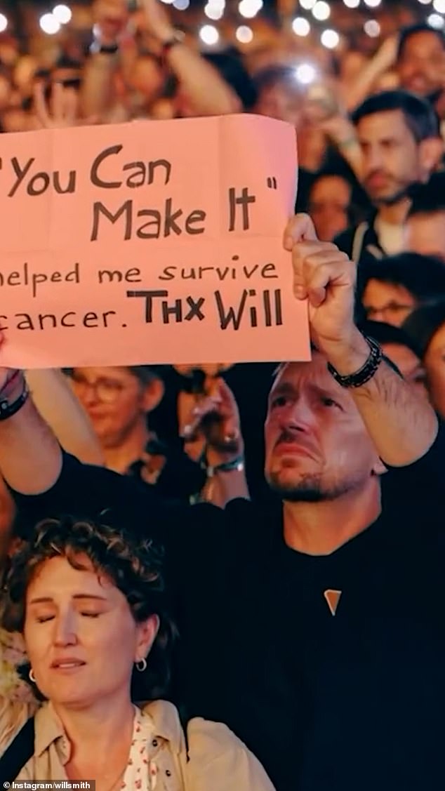 Another part of the clip shows a man's knuckle seemingly blur along with his sign, which reads: '"You Can Make It" helped me survive cancer. THX Will'