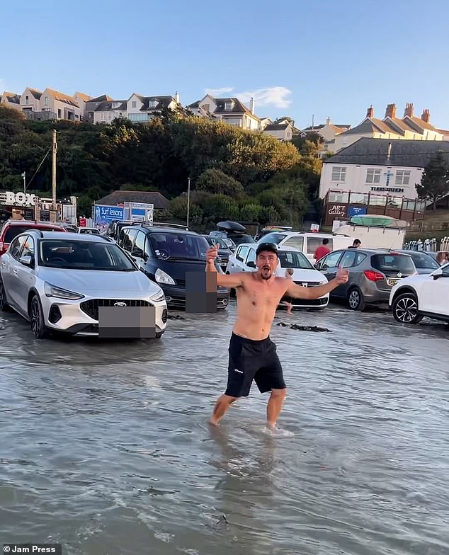 Panicked drivers can be seen attempting to salvage their motors while children danced excitedly around the vehicles and bemused grown-ups posed in front of the site