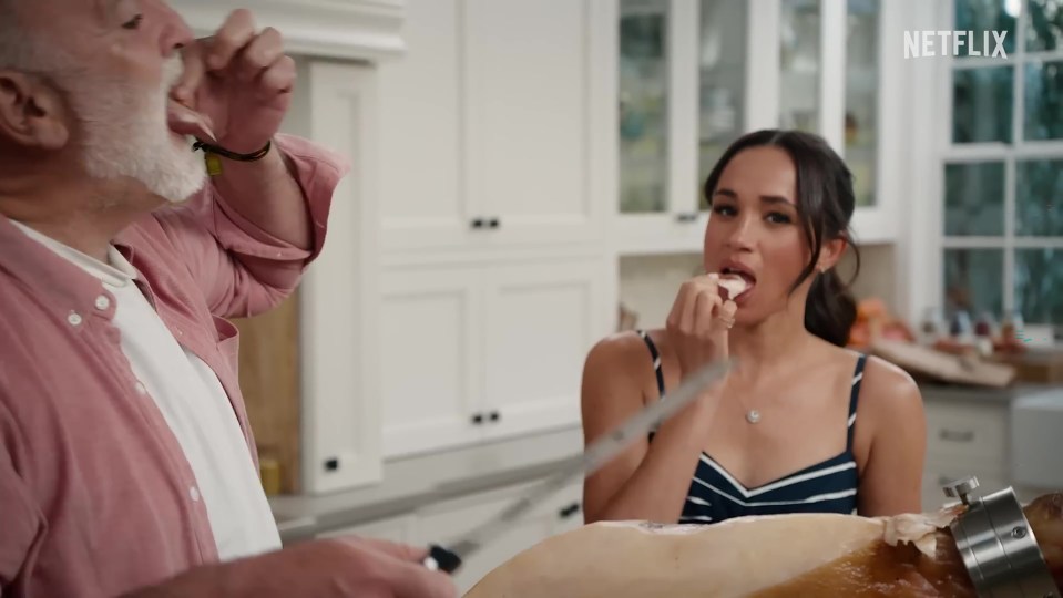 Meghan Markle and an older man eating jamon in a kitchen.