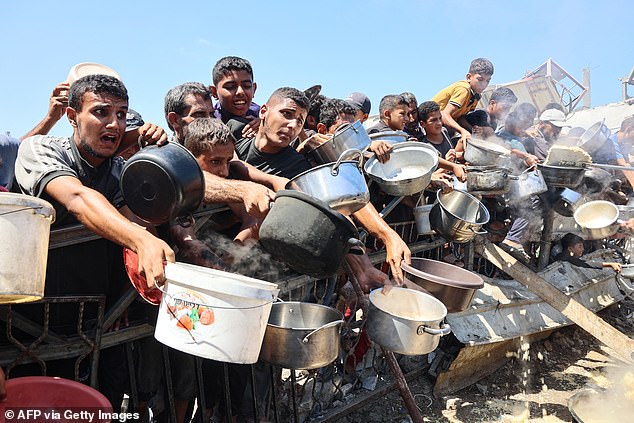 The report said starvation in the Strip 'is present and rapidly spreading' (Pictured: Palestinians desperately waiting for food on August 21)