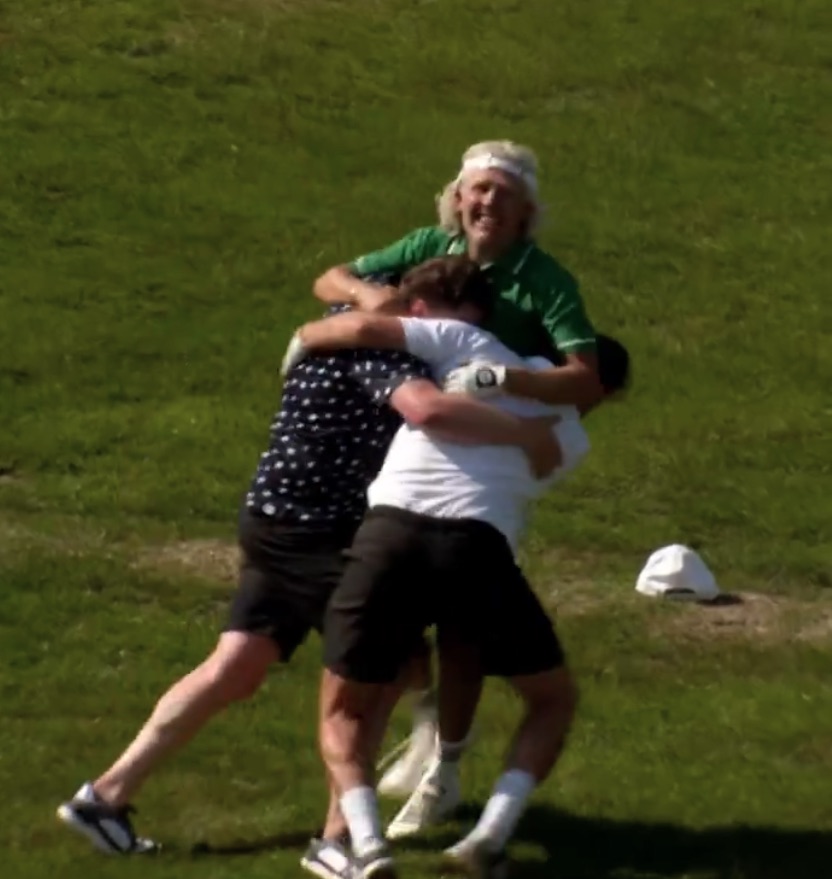 Three men embracing on a golf course.