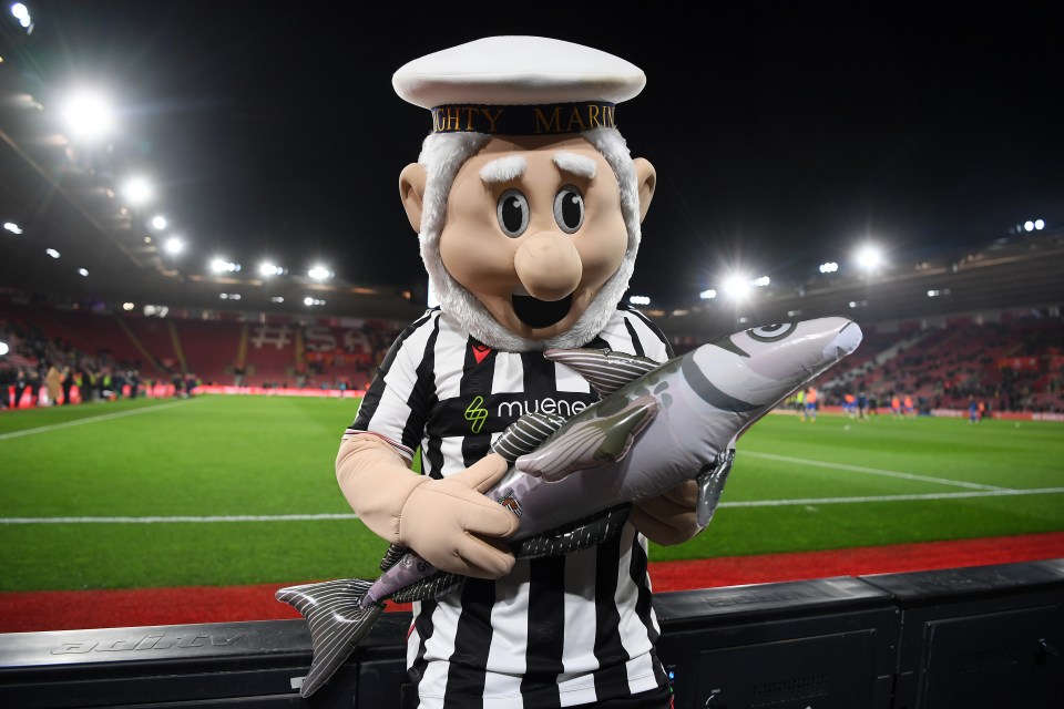 Grimsby Town's mascot, The Mighty Mariner, holding an inflatable fish at a soccer game.