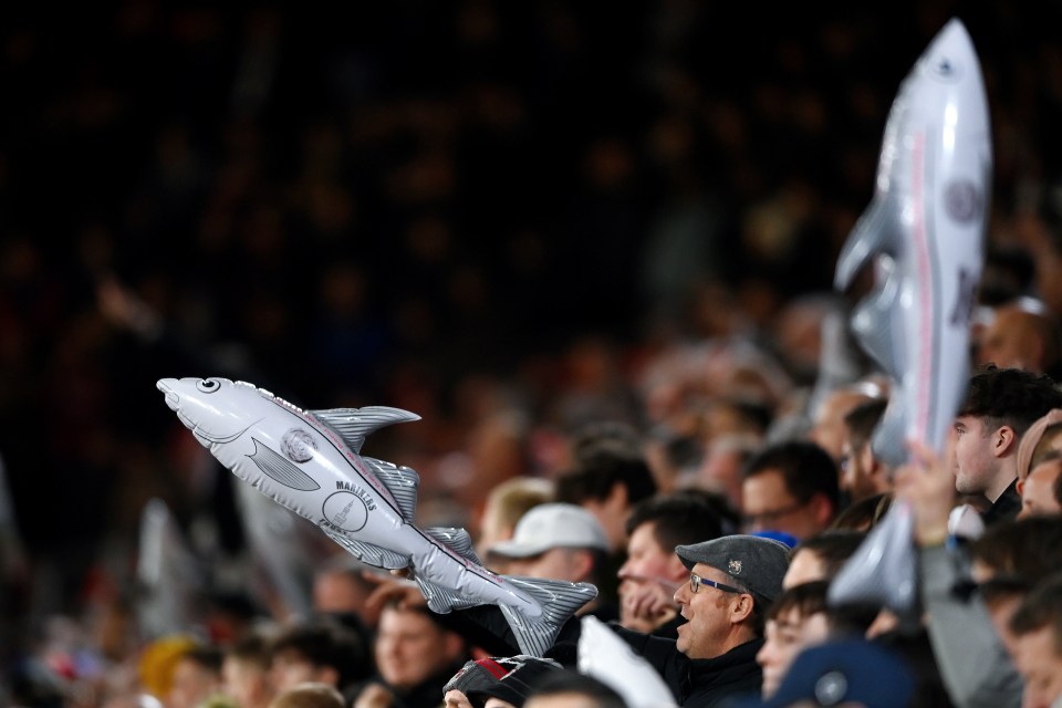 Grimsby Town fans holding inflatable fish at a soccer match.