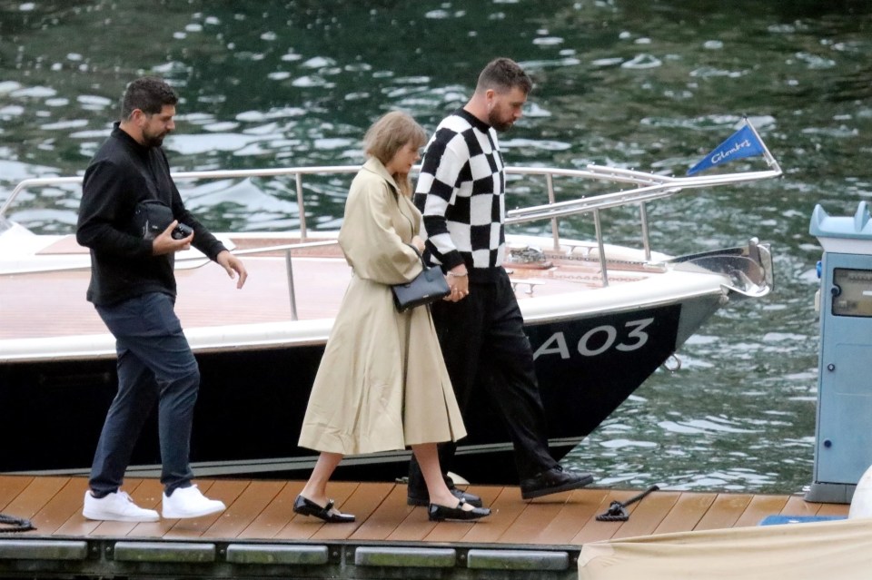 Taylor Swift and Travis Kelce holding hands and walking off a boat.