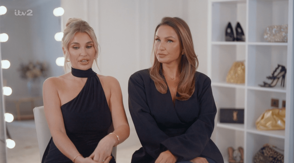 Screenshot of two women in black outfits sitting and talking.
