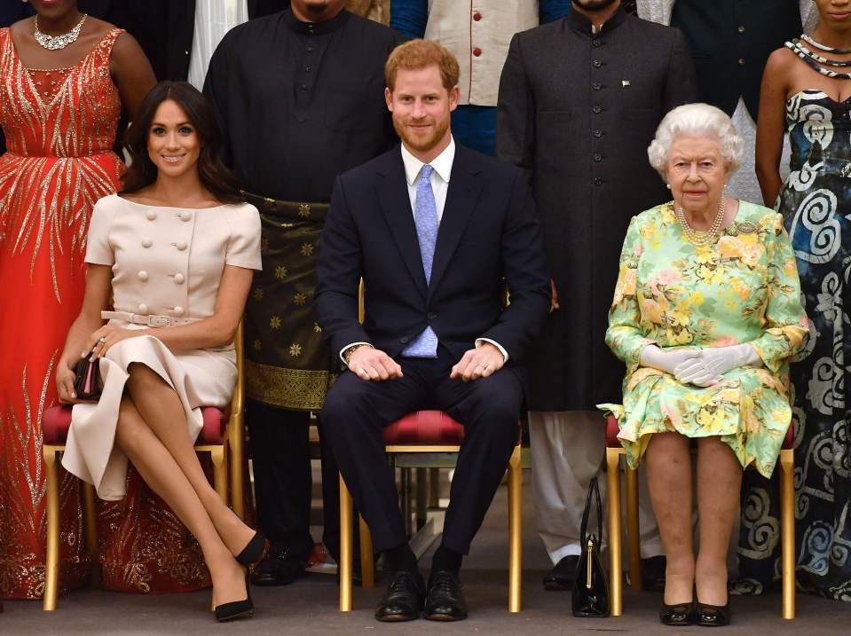 Meghan Markle, Prince Harry, and Queen Elizabeth II seated together.
