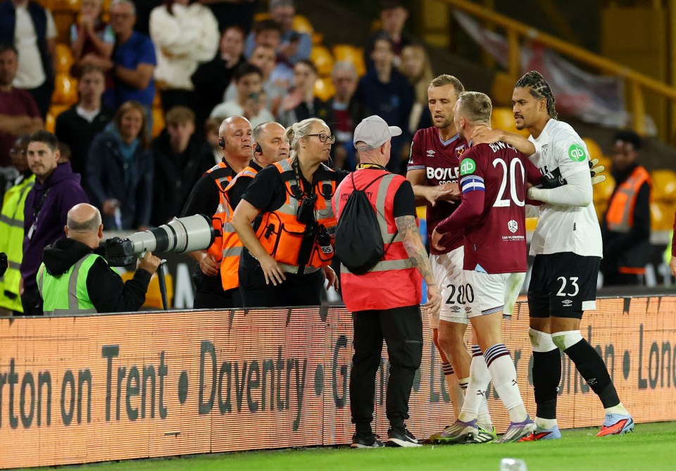 West Ham United players interacting with security and fans after a soccer match.