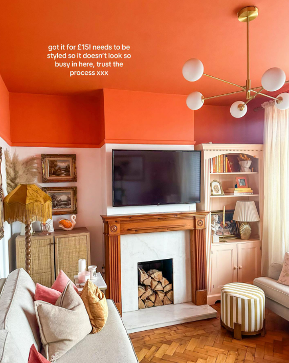 Living room with fireplace, TV, and orange ceiling.