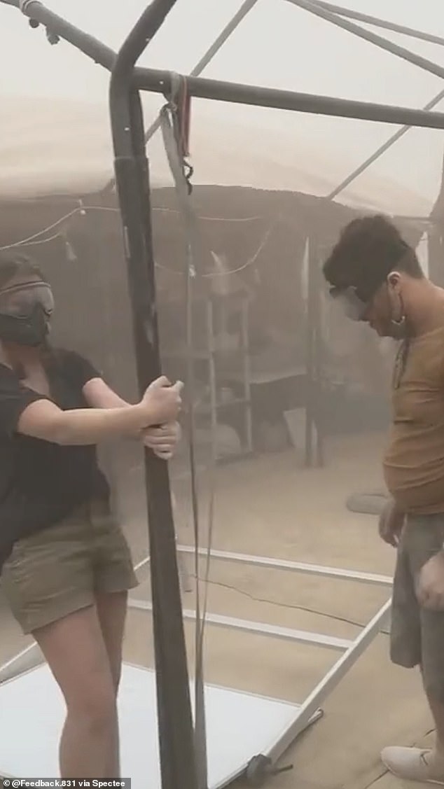 A woman wears ski goggles to prevent dust getting into her eyes as the dust storm hits the festival