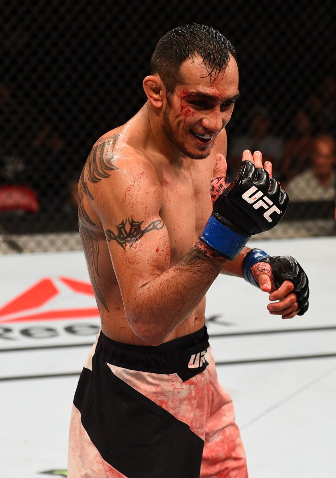Tony Ferguson, bloodied and smiling, taunts his opponent after a UFC fight.