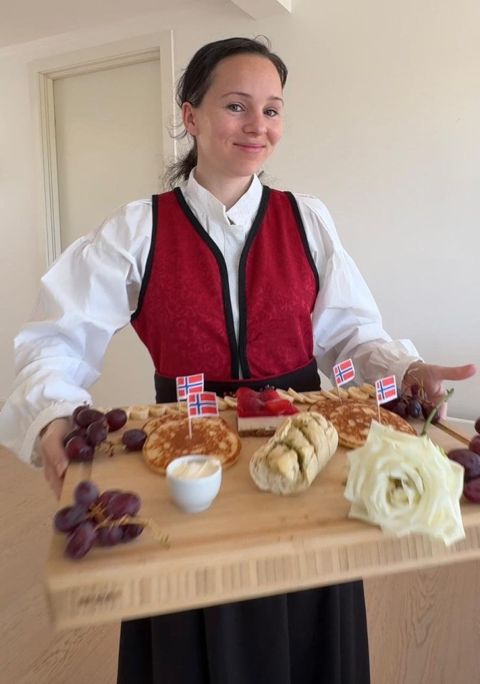 Woman in traditional Norwegian clothing holding a platter of food.