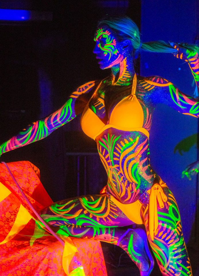 Woman in neon body paint and yellow bikini.
