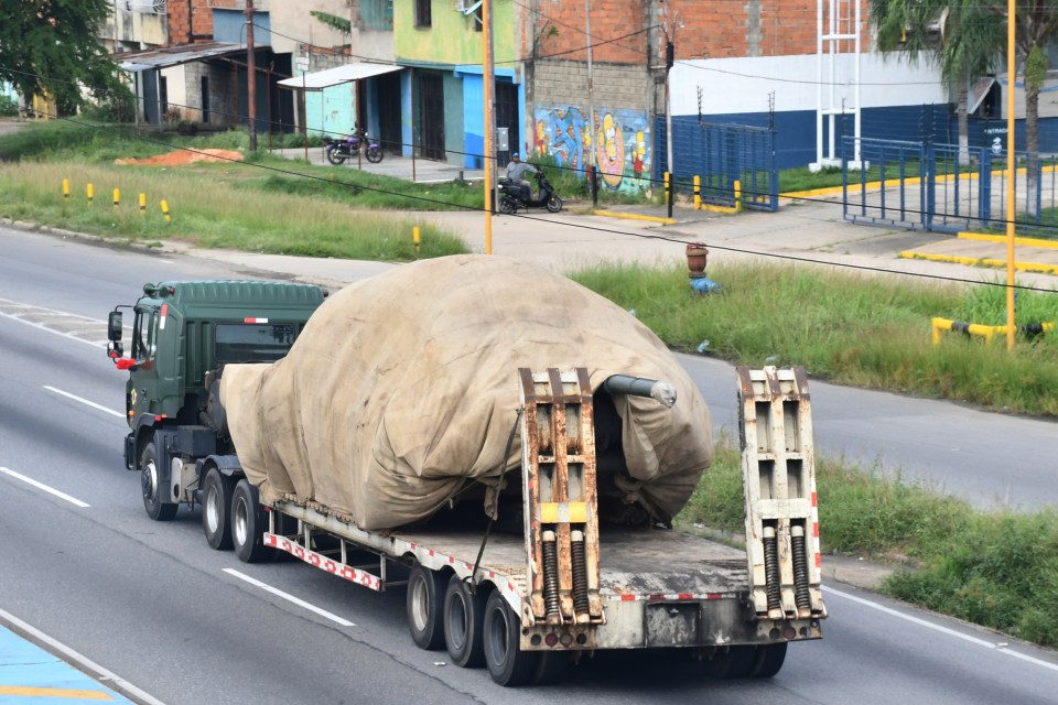 Truck transporting a covered military tank.