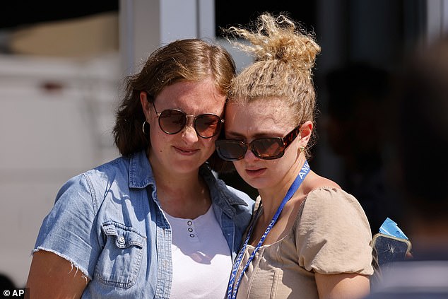 Pictured: Parents embracing after the deadly shooting killed two children on Wednesday