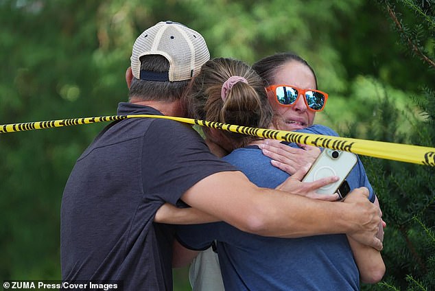 Community members are pictured embracing after the shooting left two young children killed