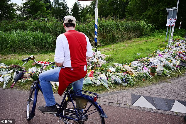 A person bikes by an improvised memorial for 17-year-old Lisa from Abcoude, at Holterbergweg, where she was found dead, in Amsterdam