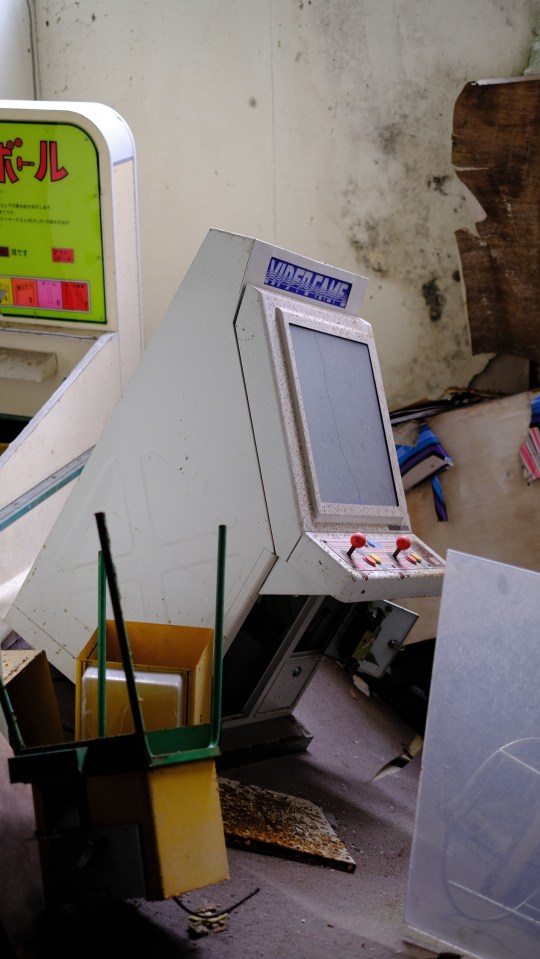 Damaged video arcade game in an abandoned hotel.