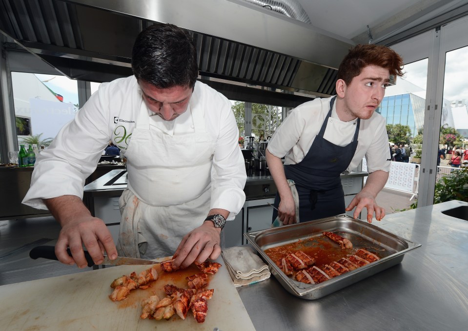 Two chefs preparing food in a kitchen.