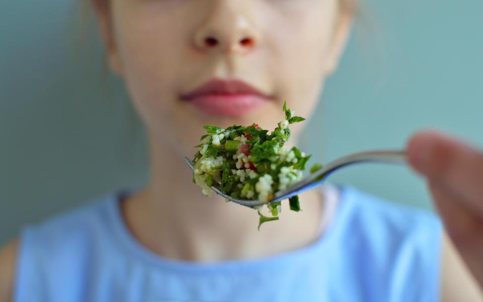 Girl eating a salad with a fork.