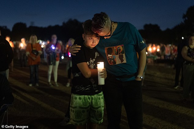Pictured: People mourn the two children, aged eight and 10, who were killed in the shooting at a vigil in Lynnhurst Park, Minnesota on Wednesday evening