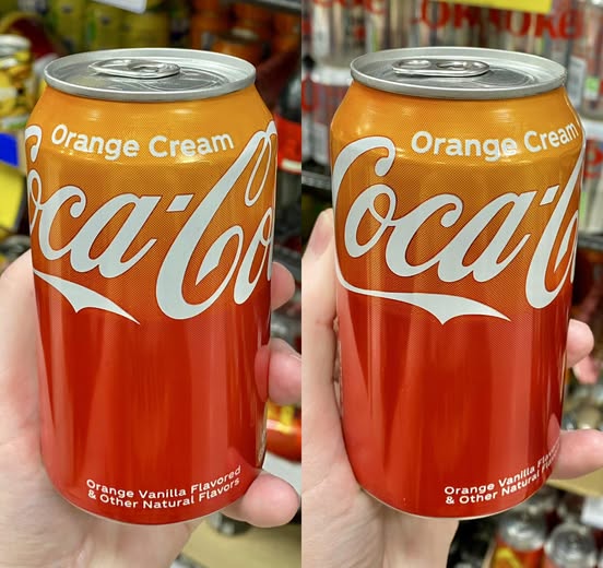 Two orange Coca-Cola cans labeled "Orange Cream."