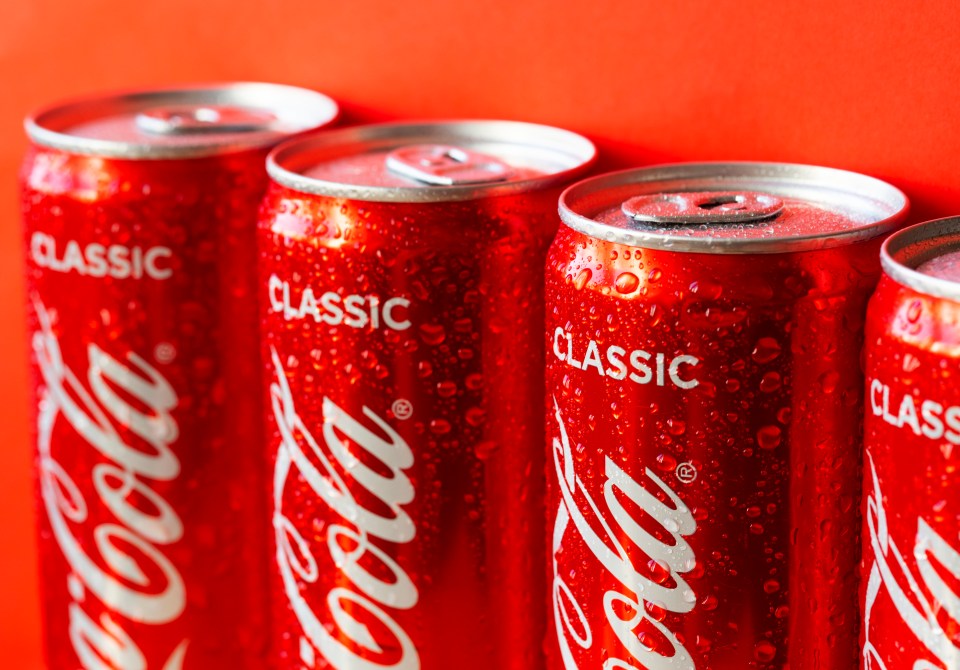 Close-up of several Coca-Cola cans covered in condensation.