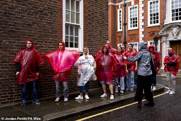 A group of tourists in ponchos shelter from the rain in Westminster yesterday