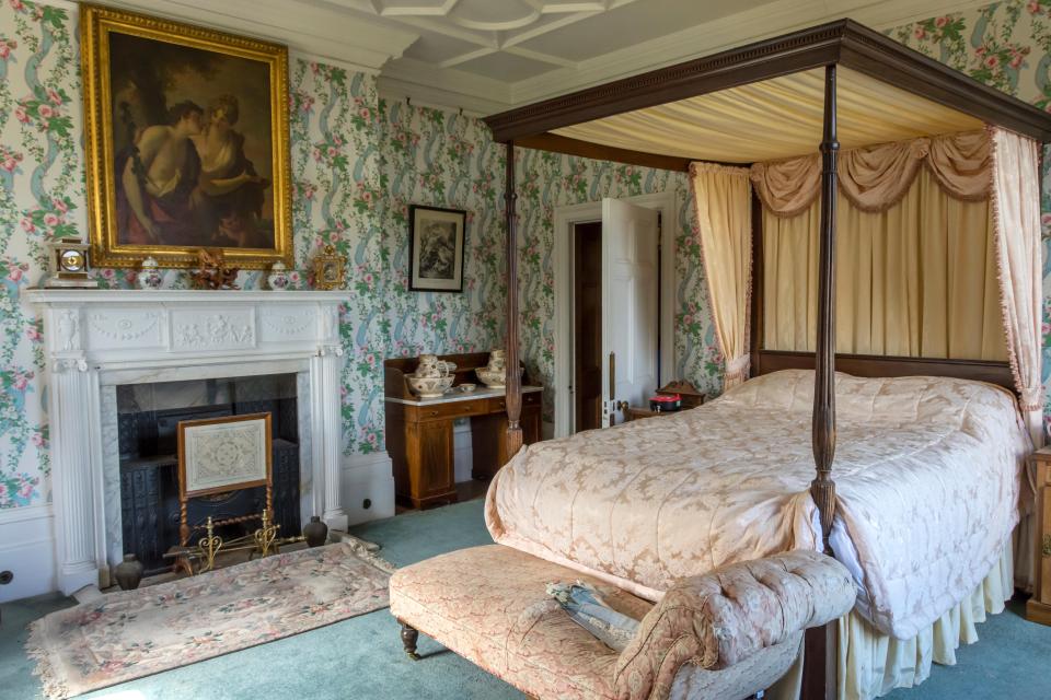 Four-poster bed in a bedroom with floral wallpaper.