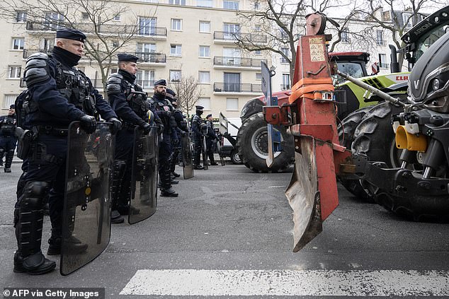 French Republican Security Corps police officers (L) stand next to tractors during a demonstration of French farmers of the Coordination Rural agricultural union, ahead of the opening of the 60th International Agriculture Fair on the Avenue de Versailles, western Paris, on February 23, 2024