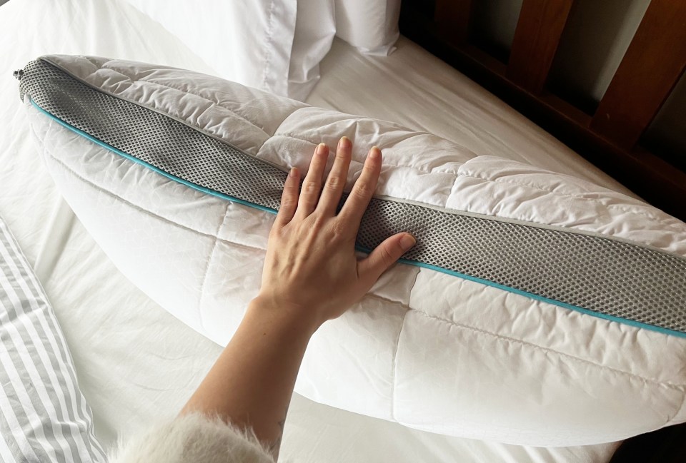 Hand on a white pillow with a gray and teal mesh insert.
