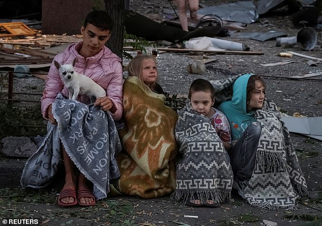 Children sit at the site of an apartment building that was hit during the deadly strikes
