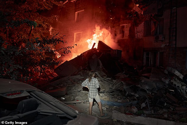 A resident looks on as fire burns in an apartment building after Russia's overnight attacks
