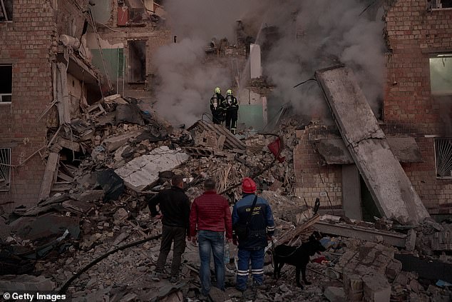 Emergency workers approach a damaged residential building hit by the strikes