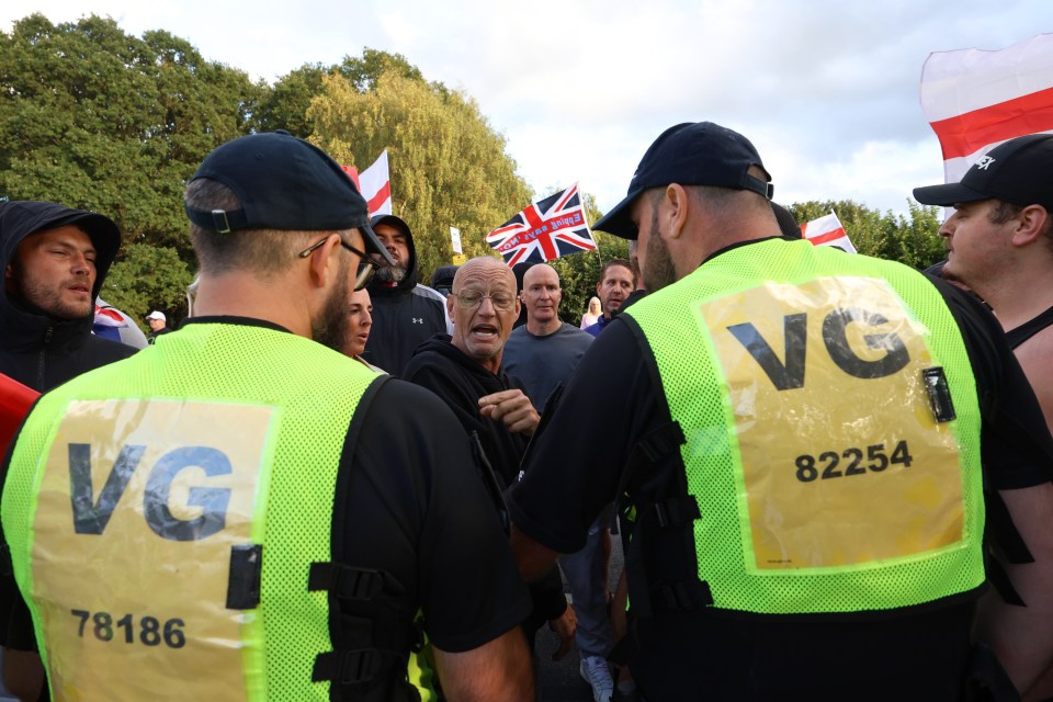 Police officers restrain protesters.