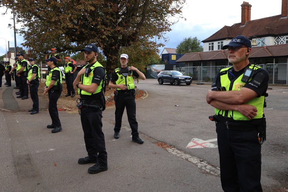 Police officers standing in a line outside a hotel.