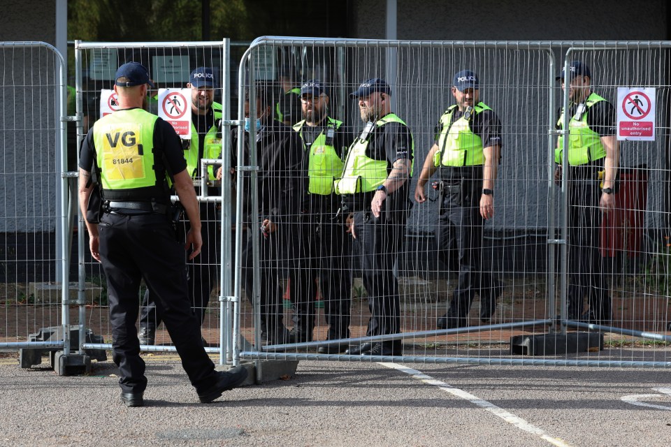 Police officers behind a fence at a protest.
