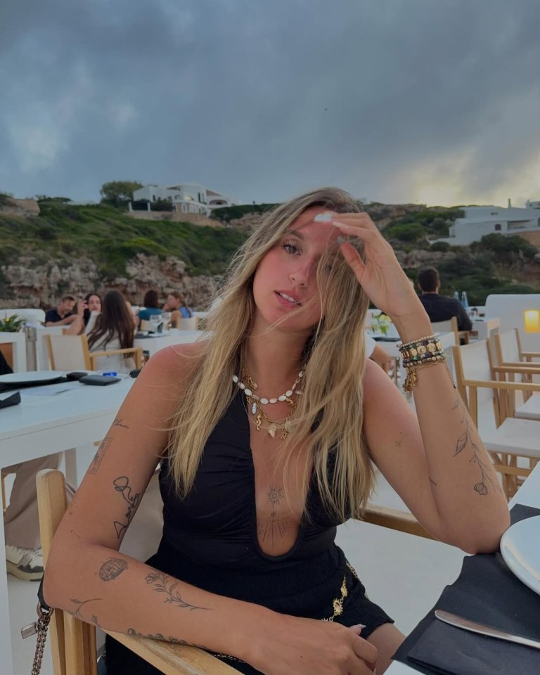 Woman with blond hair and tattoos sitting at an outdoor restaurant.