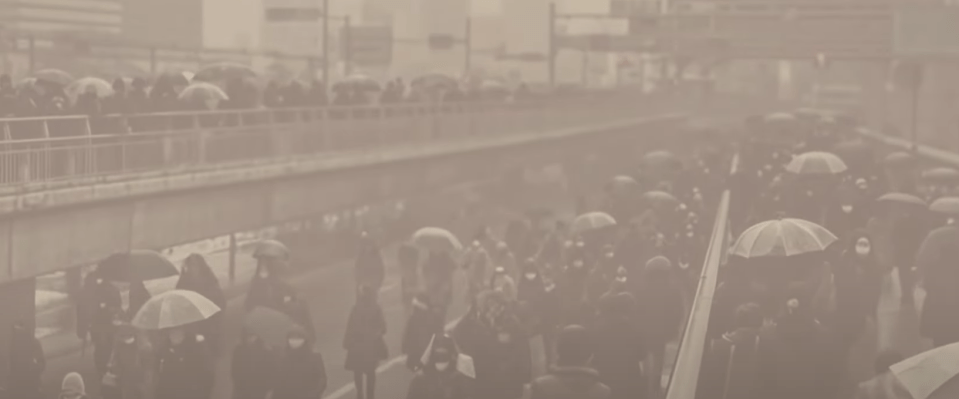 People with umbrellas walking in a foggy city.